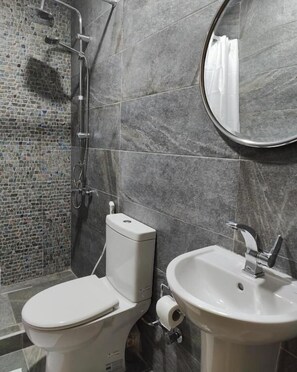 A bathroom with a mosaic shower wall, a toilet, a sink, and a mirror. - Champollion Palace Hotel (Cairo)