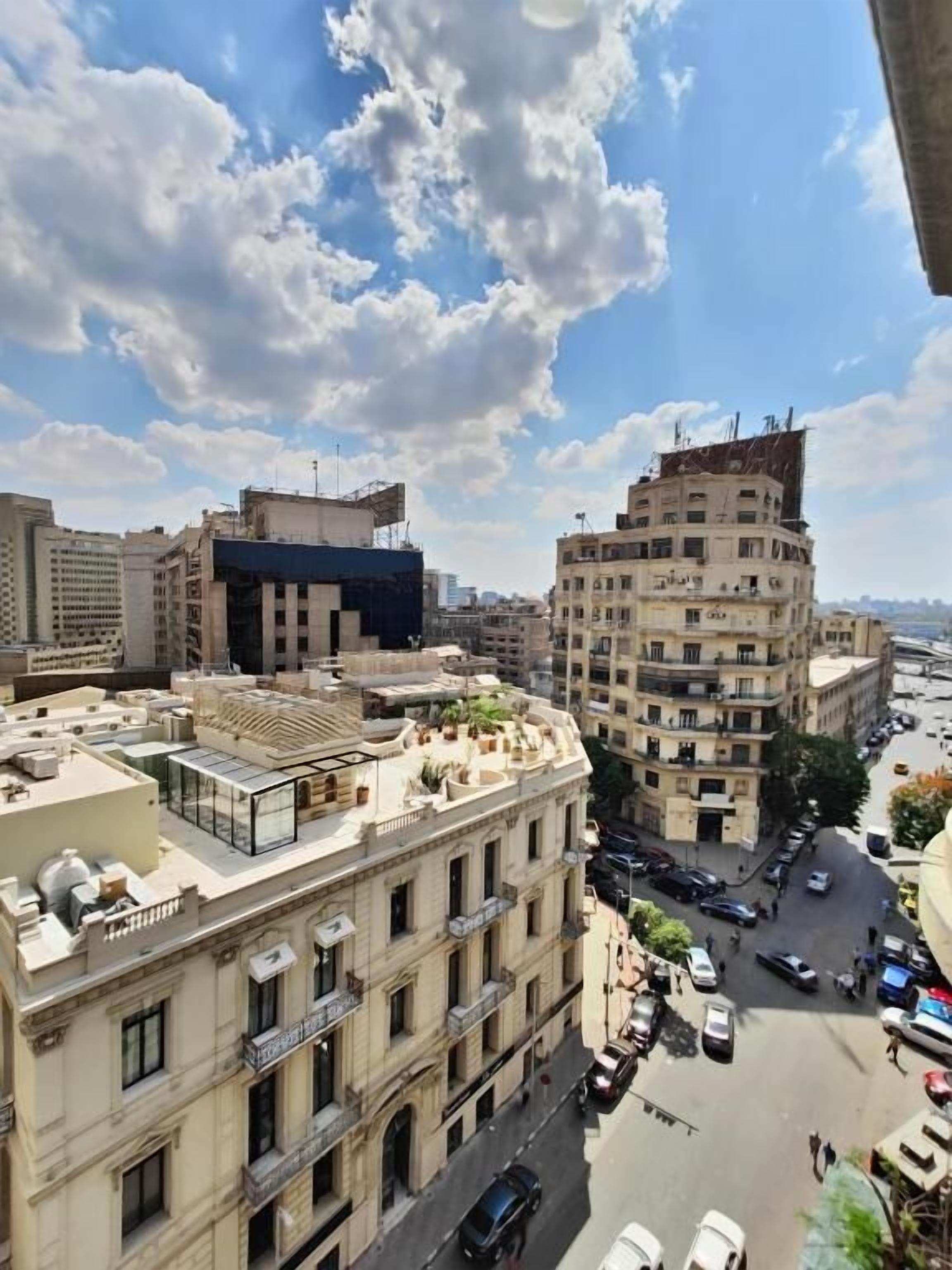 Un immeuble à plusieurs étages présentant un mélange de styles architecturaux, notamment une façade classique ornée de colonnes et une structure moderne dotée d’un toit plat.