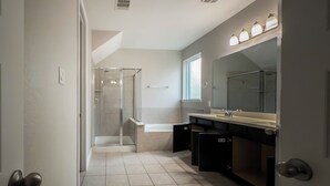 Un baño moderno con cabina de ducha de vidrio, un espejo grande y un mueble de tocador con lavabo.