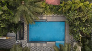 An aerial view of a rectangular swimming pool surrounded by lush greenery and a patterned tiled walkway. - D'WAYFARER INN Resort  (Erode)