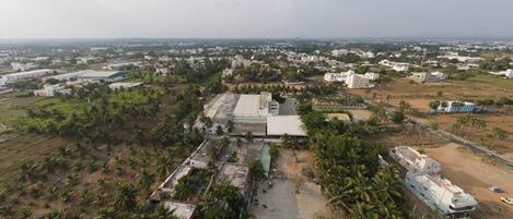 Vista aérea de uma área residencial com vários edifícios, incluindo uma construção grande com telhado plano e piscina.