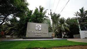A sign for D'Wayfarer Inn Resort with a logo, surrounded by greenery and palm trees. - D'WAYFARER INN Resort  (Erode)