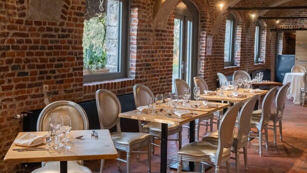 Un restaurante con paredes de ladrillo, ventanas arqueadas y mesas dispuestas para comer.