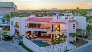 Uma casa moderna de dois andares com piscina, área de estar ao ar livre e vista para as montanhas.
