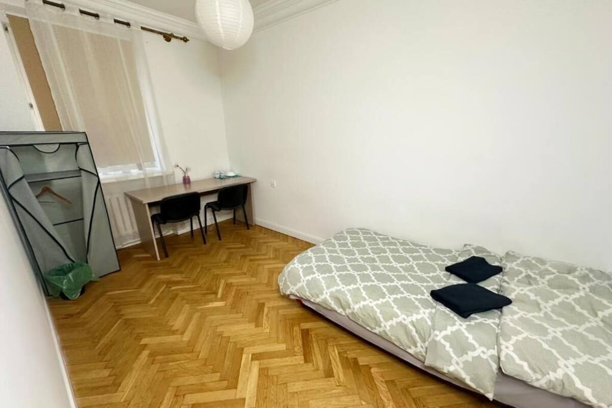 A bedroom with a bed, a desk, and a chair.
