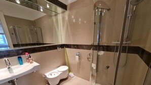 Un baño moderno con ducha acristalada, lavabo blanco y retrete.