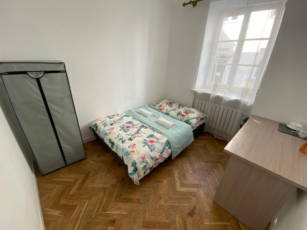 Una habitación pequeña con una cama, un radiador, una ventana y un escritorio.