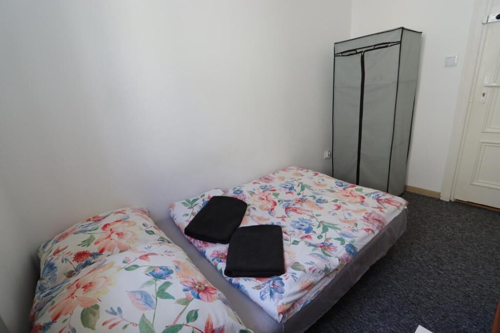 A small room with a single bed, a wardrobe, and a carpeted floor.