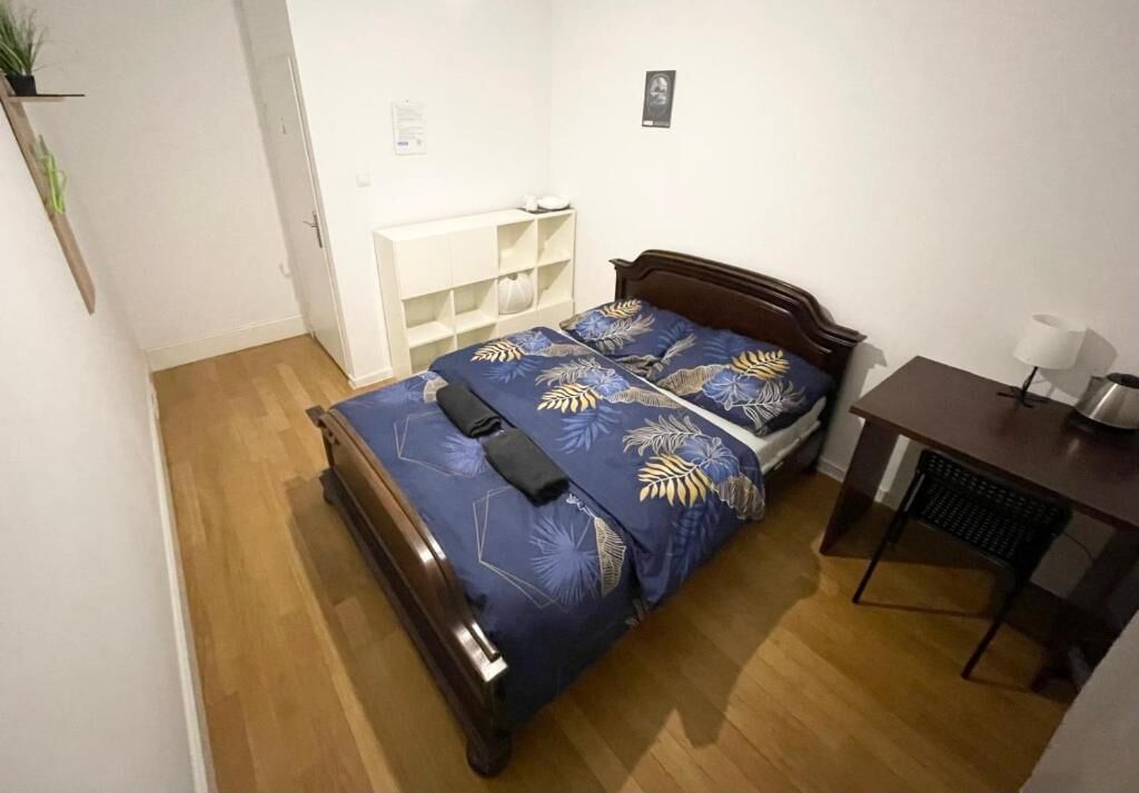 Un dormitorio pequeño y ordenado con cama de madera, un escritorio y una estantería.