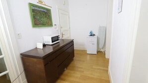 Una habitación con un aparador de madera, microondas, un mueble pequeño y un cuadro en la pared.