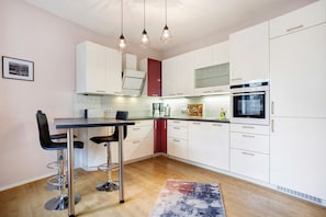 A modern kitchen with white cabinets, a stainless steel oven, and a bar area with stools. - Apartment "Flür" with Private Terrace and Wi-Fi (Weiler-Simmerberg)