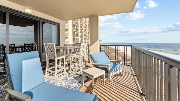 A balcony with a view of the beach, furnished with chairs and tables. - Romar House 601A by Liquid Life (Orange Beach)