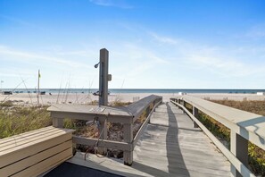 A wooden boardwalk leading to a beach with a lifeguard tower and a bench. - Romar House 601A by Liquid Life (Orange Beach)