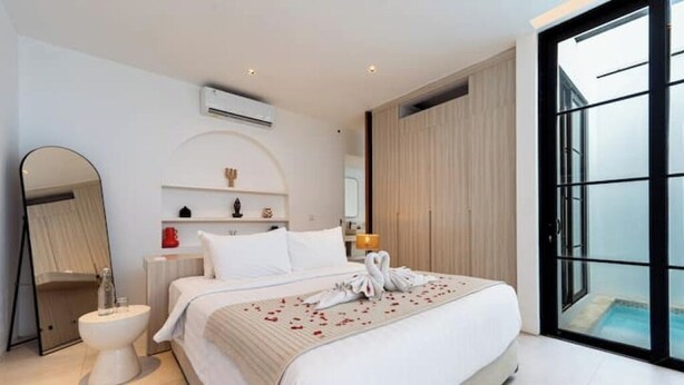 Een moderne hotelkamer met een groot bed, een nachtkastje, een spiegel, een toilet en uitzicht op een zwembad door een glazen deur.