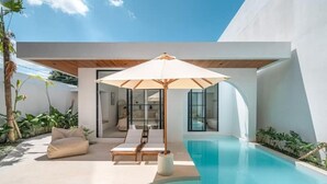 Een modern zwembad met ligbedden en een grote parasol.