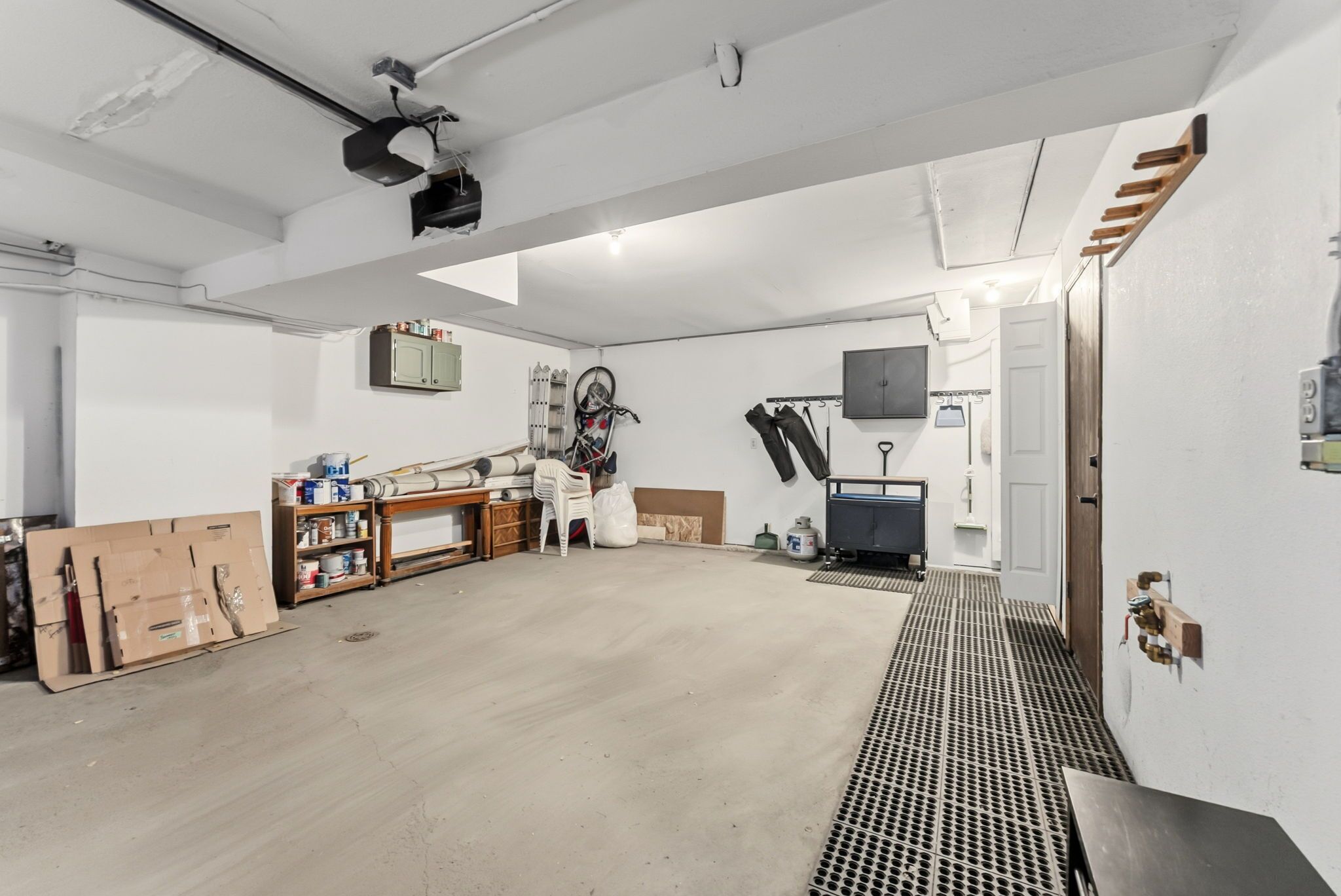 A spacious room with a concrete floor, a mounted projector, and a bicycle leaning against the wall.