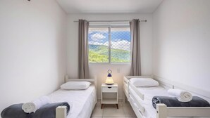 A small, clean room with two beds, a nightstand with a lamp, and a window with curtains. - Apt w/ Barbecue Grill 750m From the Beach Evp0504 (Itapema)