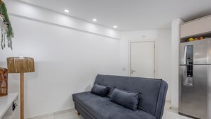 A modern living room with a grey sofa, a floor lamp, and a stainless steel refrigerator. - Apt w/ Barbecue Grill 750m From the Beach Evp0504 (Itapema)