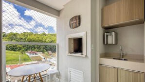 A kitchen with a view of a green landscape, a clock, and a small window. - Apt w/ Barbecue Grill 750m From the Beach Evp0504 (Itapema)