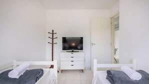 A bedroom with two beds, a TV on a dresser, and a mirror on the wall. - Apt w/ Barbecue Grill 750m From the Beach Evp0504 (Itapema)