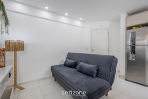 A modern living room with a grey sofa, a floor lamp, and a stainless steel refrigerator. - Apt w/ Barbecue Grill 750m From the Beach Evp0504 (Itapema)