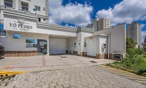 A building with a sign reading "VÔ PEDRO RESIDENCIAL" and multiple garage doors. - Apt w/ Barbecue Grill 750m From the Beach Evp0504 (Itapema)