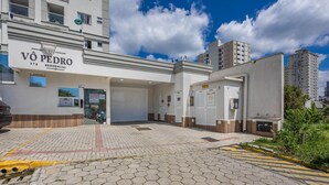 A building with a sign reading "VÔ PEDRO RESIDENCIAL" and multiple garage doors. - Apt w/ Barbecue Grill 750m From the Beach Evp0504 (Itapema)
