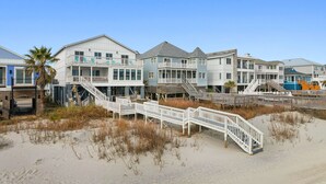 Une propriété située en bord de mer, comprenant plusieurs bâtiments, notamment une grande maison dotée d’un balcon et une plus petite maison avec une véranda.