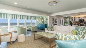 Un vaste espace de vie avec une grande fenêtre donnant sur la plage, une cuisine moderne et un coin salon confortable.