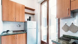 A kitchen with wooden cabinets, a white refrigerator, and a marble countertop. - Terrazza Rooftop (Como)