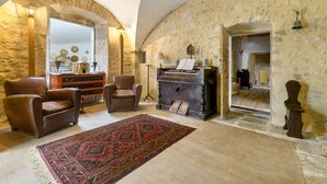 Una habitación con paredes de piedra, chimenea, sillones de cuero y una alfombra estampada.