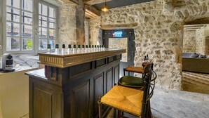 Una zona de bar con pared de piedra, mostrador de madera y taburetes.