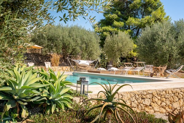 Un área de piscina con sillas de descanso y un muro de piedra.