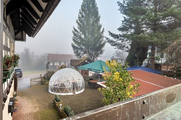 A gazebo, a tennis court, and a large tree in a residential setting.