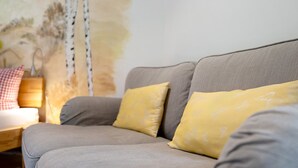 A sofa with a cushion, a wooden side table, and a lamp. - Room “Birke” with Shared Garden and Wi-Fi (Sasbachwalden)