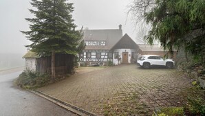 A traditional half-timbered house with a paved driveway and a parked white car. - Room “Birke” with Shared Garden and Wi-Fi (Sasbachwalden)