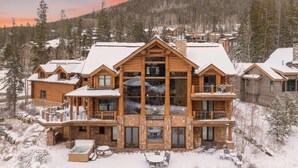 A large log cabin with multiple balconies, a hot tub, and outdoor seating. - Forest Setting | Near Trail Access (Winter Park)