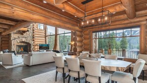 A spacious log cabin interior with a stone fireplace, a large dining table, and a cozy seating area. - Forest Setting | Near Trail Access (Winter Park)