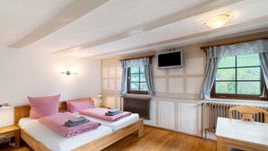 A bedroom with a double bed, bedside tables, a TV mounted on the wall, and a window with curtains. - Room “Buche” with Shared Garden and Wi-Fi (Sasbachwalden)