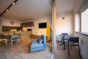 Ein moderner Wohnbereich mit Küche, Essbereich und einem Balkon mit Sitzgelegenheit.