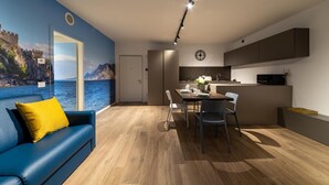 Una sala de estar moderna con un sofá azul, un comedor con mesa y sillas, una cocina con armarios, y un ventanal con vistas panorámicas.