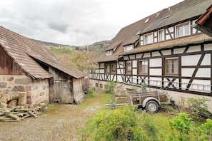 Un edificio tradicional con entramado de madera, un patio de grava, estructuras de madera y un carruaje.