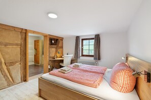 Un dormitorio con una cama de madera, un escritorio, una silla, un radiador y una ventana con cortinas.