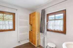 A bathroom with a wooden wardrobe, a white radiator, a window with a view of trees, and a white sink. - Room “Oak” with Shared Garden and Wi-Fi (Sasbachwalden)