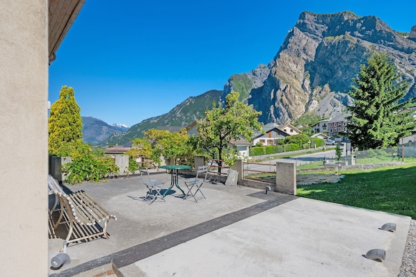 A patio with outdoor furniture, a mountain backdrop, and a view of residential buildings.