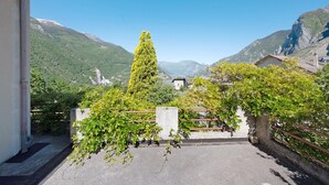 Ein Innenhof mit Bergblick, ein hoher Baum und ein Gebäude mit einem geneigten Dach.