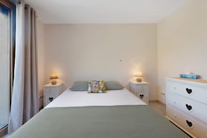 A bedroom with a bed, two bedside tables with lamps, a dresser with heart-shaped drawers, and a window with curtains. - Maison Casabert Savoie: Modern Comfort in a Charming Mountain Setting (Saint-Martin-de-la-Porte)