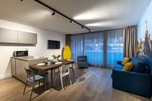 Un soggiorno moderno con angolo da pranzo, un divano, una poltrona, una televisione e un'area cucina con forno a microonde.