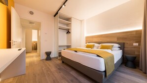 A modern hotel room with a bed, bedside table, and a walk-in closet. - Apartment 'Boutique Yellow' with Balcony, Wi-Fi and Air Conditioning (Nago-Torbole)