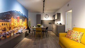 A modern kitchen with a dining area, a yellow sofa, and a wall clock. - Apartment 'Boutique Yellow' with Balcony, Wi-Fi and Air Conditioning (Nago-Torbole)